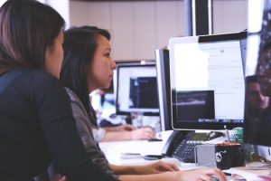 Two women working at a computer in a clean work environment