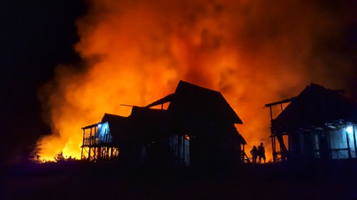 Fire Restoration Services look on as a terrible fire engulfs a beautiful house.
